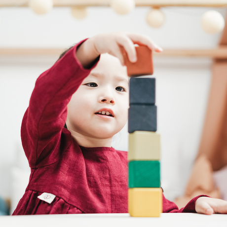 Un jeune enfant empile des blocs.