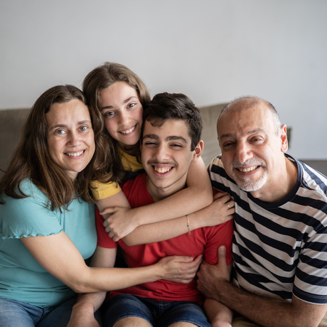 Photo d’une famille à la maison, avec leur enfant autiste.