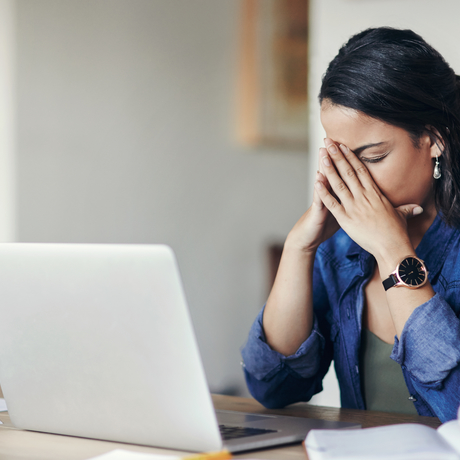 Une femme semblant stressée tout en utilisant un ordinateur portable.